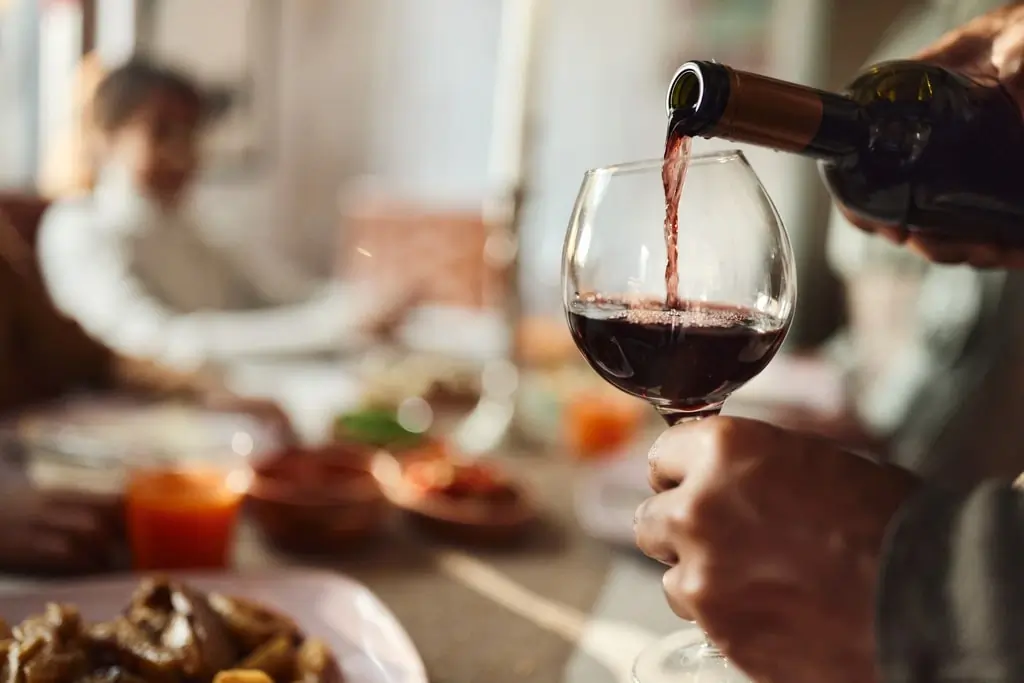 Red wine being poured into a glass at Agio Bar, showcasing the restaurant's wine selection
